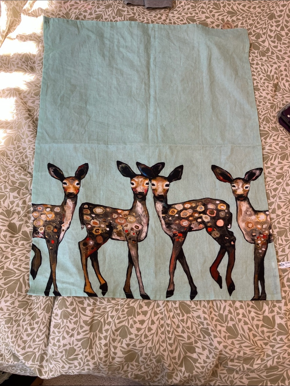 This is a decorative tea towel featuring artwork by Eli Halpin, 5 Dancing Fawns